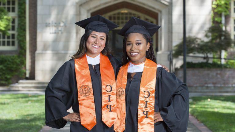 two Community Involvement Program scholars in commencement regalia 